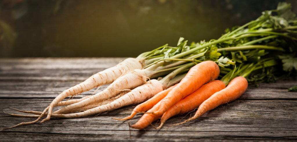 Fresh So Sweet carrots and parsnips on a wooden chopping board, ready to prepare.