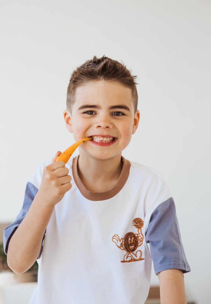A young boy eating a fresh carrot to promote healthy fundraising in New Zealand with So Sweet.