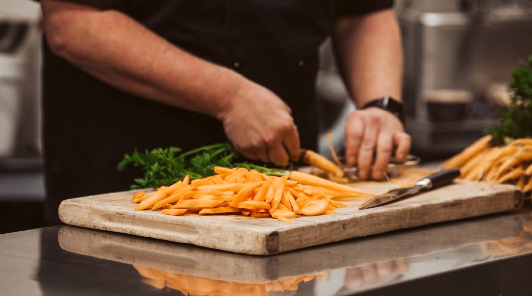 Chef preparing freshly cut carrots in a commercial kitchen, demonstrating food service collaboration with So Sweet produce Chef preparing freshly cut carrots in a commercial kitchen, demonstrating food service collaboration with So Sweet produce