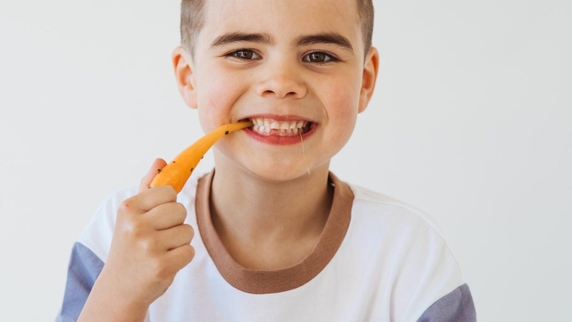 A young boy eating a fresh carrot to promote healthy fundraising in New Zealand with So Sweet.