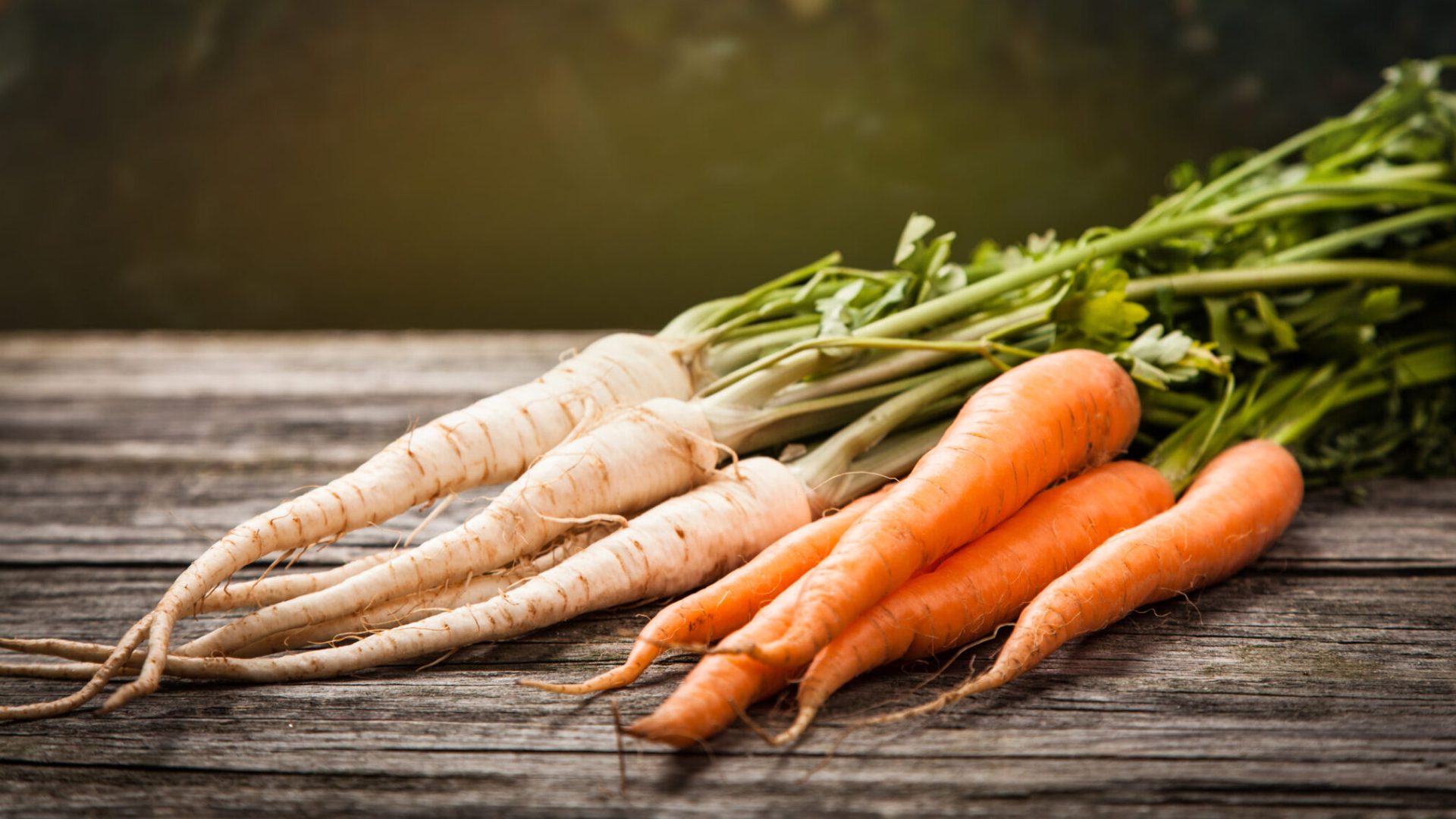 Fresh So Sweet carrots and parsnips on a wooden chopping board, ready to prepare.